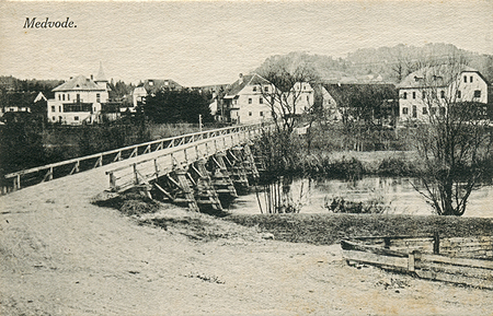 Most čez Soro in občinska stavba v ozadju leta 1930 (razglednico hrani Knjižnica Medvode)